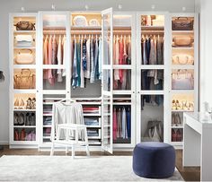 an organized closet with clothes and handbags on the shelves in front of it, along with a footstool