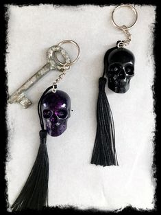 two skull keychains with tassels and a skeleton head on one side