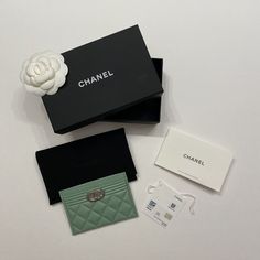 the contents of a chanel purse are laid out on a white table with black and green boxes