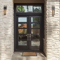 the front door to a home with two glass doors and a rug on the sidewalk