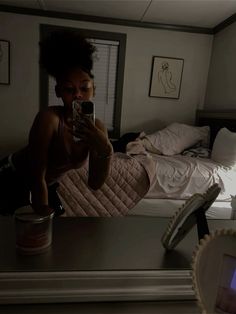 a woman taking a selfie with her cell phone in the dark, while sitting on a bed