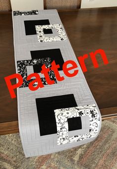 a table runner with the letters f and p in black and white quilted on it