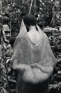 a black and white photo of a woman wrapped in a crochet shawl