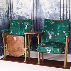 two green chairs sitting next to each other in front of a wooden table and wall