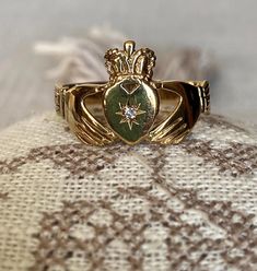 a gold ring with a green heart and a star on it sitting on a lace covered surface