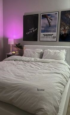 a white bed sitting in a bedroom next to two posters