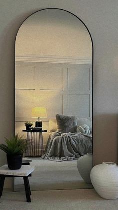 a bedroom with a large mirror on the wall next to a small table and lamp