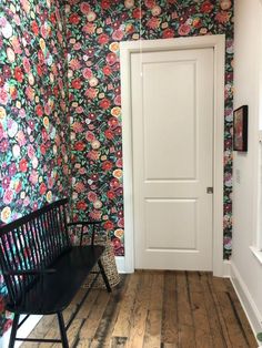 a white door sitting next to a black bench on top of a hard wood floor