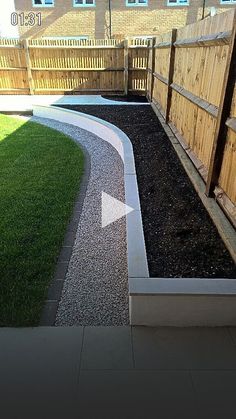 a backyard area with grass, gravel and wooden fence