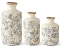 three vases with floral designs on them are lined up against a white background and one is empty