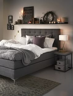 a bedroom with a bed, nightstands and pictures on the wall above it is lit by candles