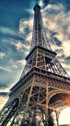 the eiffel tower in paris, france is shown against a cloudy blue sky