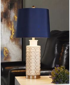 a table lamp sitting on top of a wooden table next to a black leather chair