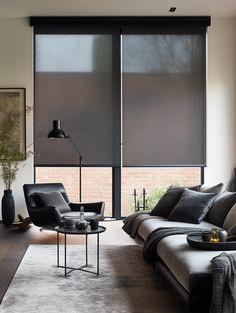 a living room with couches, chairs and windows covered in blinds that look out onto the outside