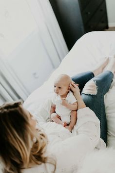 a woman laying on top of a bed holding a baby