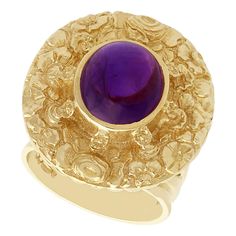 An impressive vintage 3.77 carat amethyst and 9 karat yellow gold cocktail ring; part of our diverse amethyst jewelry and estate jewelry collections. This fine and impressive vintage amethyst ring has been crafted in 9k yellow gold. The ring has an oval form, embellished with a textured floral design. The center of the floriated design is ornamented with a feature 3.77Ct oval cabochon cut amethyst, bezel set in relief. The multi-stranded, pierced decorated and shaped ring shoulders integrate wit Luxury Round Cabochon Amethyst Ring, Formal Cabochon Amethyst Ring Fine Jewelry, Luxury Amethyst Cabochon Ring, Polished Vintage Amethyst Ring, Elegant Gold Amethyst Cabochon Ring, Gold Amethyst Ring With Cabochon Cut, Luxury Collectible Amethyst Ring, Vintage Amethyst Rings With Polished Finish, Elegant Yellow Gold Cabochon Amethyst Ring