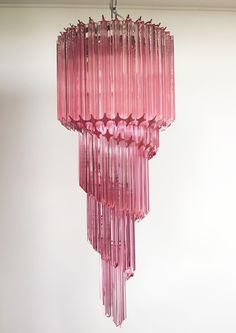 a pink chandelier hanging from the ceiling in a room with white walls and flooring