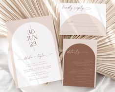 the wedding stationery is laid out on top of a white plate with palm fronds