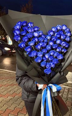 a woman holding a bouquet of blue roses in her hands and heart shaped flowers on the back