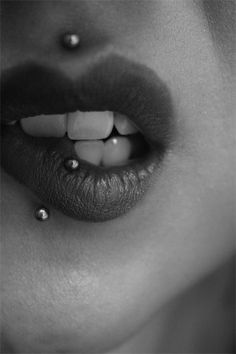 a black and white photo of a woman's mouth with the lip piercing on