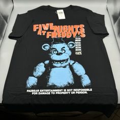 Five Nights At Freddy's Jumbo Print T-Shirt Small If You're Heading To The Pizzaplex For A Night Of Fun, Make Sure You're Rockin' A Killer Shirt! This Five Nights At Freddy's Tee Features Freddy Fazbear In A Tonal Print, With The Game Name Up Top In Bold And A Disclaimer At The Bottom. * 100% Cotton * Wash Cold; Dry Low * Imported * Listed In Men's/Unisex Sizes Game Name, Tonal Prints, Freddy Fazbear, Five Nights At Freddy's, Five Night, The Game, New Color, Tshirt Print, Print T Shirt