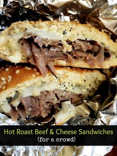 there is a sandwich with meat and cheese in the wrapper on tin foil that says hot roast beef & cheese sandwiches for a crowd