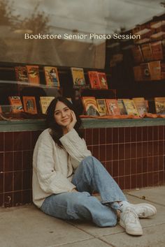 a woman sitting on the ground in front of a book store with her hand under her chin