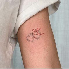 a couple of hearts tattoo on the right arm and left arm with a red ribbon around it