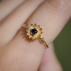 a woman's hand with a yellow and blue flower ring on it, showing the center stone