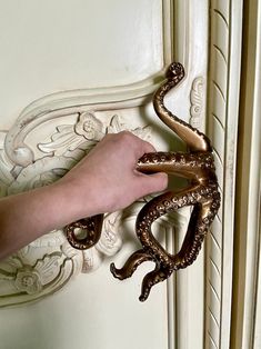 a hand reaching for an octopus on the door handle to catch it's own tail