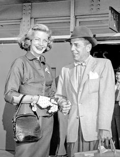 an old black and white photo of a man and woman in suits talking to each other