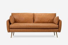 a tan leather couch with two pillows on it's back and one arm extended