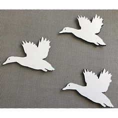 three white birds are flying in the air