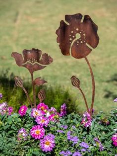 two metal flowers are in the middle of some purple flowers