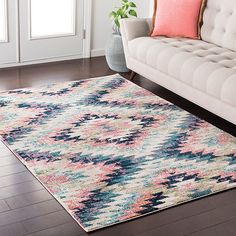 a living room with a white couch and colorful rugs on the hardwood flooring