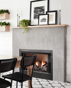 a fire place in the middle of a room with chairs and pictures on the wall