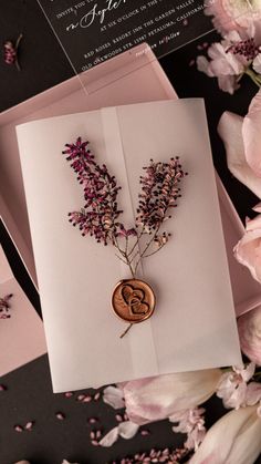 the wedding card is decorated with flowers and a wax stamp on it's front