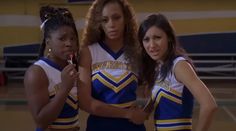 three young women in cheer uniforms standing on a basketball court