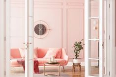 a living room with pink walls and a clock on the wall above the couches