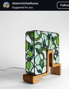 a lamp that is sitting on top of a wooden stand and has green leaves painted on it