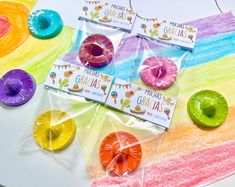 four different colored doughnuts in cellophane bags on top of a table