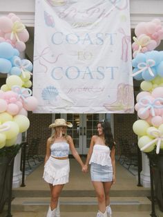 two women standing in front of a sign with balloons on it that say coast to coast