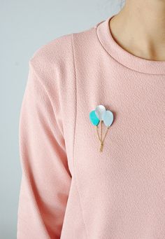 a woman wearing a pink shirt with two blue hearts on it's lapel