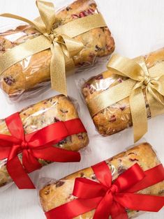 four cookies wrapped in red ribbon and tied with gold bow on white table top next to each other