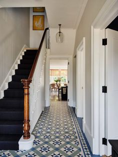 a hallway with blue and white flooring next to a stair case in a house