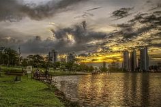 the sun is setting over a body of water with tall buildings in the back ground