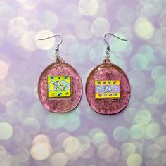 If you love Tamagotchis then you're gonna love these earrings! They're slightly transparent with glitter for that iconic Y2K look. They are kind of heavy, so just a heads up! Your earrings will arrive wrapped in tissue paper and in a clear cello bag. Try not to get them wet as the image is a sticker, if you get anything on them give them a gentle wipe.This listing is for a mismatch pair, if you want a mismatch pair be sure to check out the other listing over here!https://www.etsy.com/uk/listing/ Wacky Outfits, Jewelry Png, 30th Ideas, Diy Crafts To Do At Home, Rainbow Clothes, Style Essence, Iconic Y2k, Rad Clothes, Earrings Matching