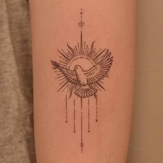 a tattoo on the arm of a woman with a bird and sunburst design