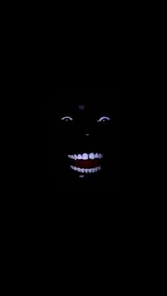 a creepy face in the dark with white teeth