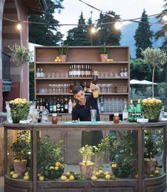 a woman standing behind a bar filled with lemons